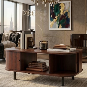 May include: A mid-century modern style coffee table made of dark wood. The table has a curved design with storage compartments and black metal legs. Books, a candle, and decorative items are displayed on the table.
