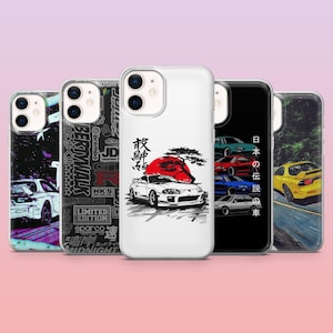 May include: Collection of phone cases with car-themed designs. One case features a white car with a red sun and Japanese text. Other cases display various car graphics and Japanese text. The cases are white, black, and clear.