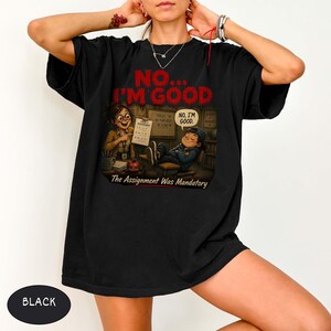May include: A black t-shirt featuring a graphic print of a classroom scene with a teacher holding a paper and a student leaning back in a chair. The text reads NO... I'M GOOD at the top, NO, I'M GOOD in a speech bubble, and The Assignment Was Mandatory.