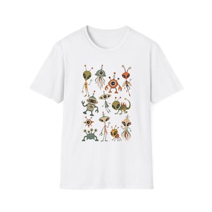 May include: A white short-sleeved t-shirt featuring a central graphic print of various colourful cartoon aliens and robots. The design includes multiple distinct extraterrestrial characters in shades of orange, green, and grey, arranged in a grid.
