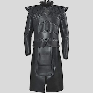 Puede incluir: Un disfraz negro de cuerpo entero con detalles intrincados. El atuendo presenta un cuello alto con volantes, detalles en los hombros y un corpiño texturizado. Las mangas largas y la falda tienen un patrón acanalado vertical y el disfraz tiene una abertura frontal.