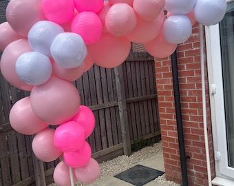 May include: A pink and white balloon arch, perfect for a party or celebration. The arch is made of various sizes of pink and white balloons, arranged in a curved shape. The balloons are supported by a white frame.