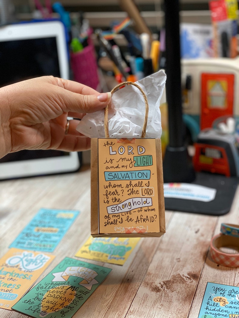 May include: A small brown paper bag with a white tissue paper inside. The bag has a printed design with the text "the LORD is my LIGHT and my SALVATION - whom shall I fear? The LORD is the Stronghold of my LIFE - of whom shall I be AFRAID? PSA 27:1".