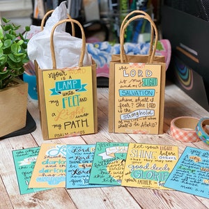 May include: A set of six small cards with inspirational bible verses written in colorful lettering. The cards are decorated with a variety of colors, including blue, green, yellow, and orange. The cards are perfect for adding a touch of faith to your home or office.