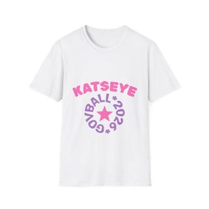 May include: White t-shirt with a graphic design. The design features the text "KATSEYE" in pink bubble letters above a purple circle with the words "GOVBALL*2026*" and a pink star in the center.