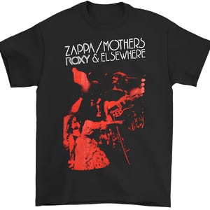 May include: Black t-shirt featuring a red graphic of a band playing instruments. The text "ZAPPA / MOTHERS ROXY & ELSEWHERE" is printed in white across the top. The shirt is a classic crew neck style.
