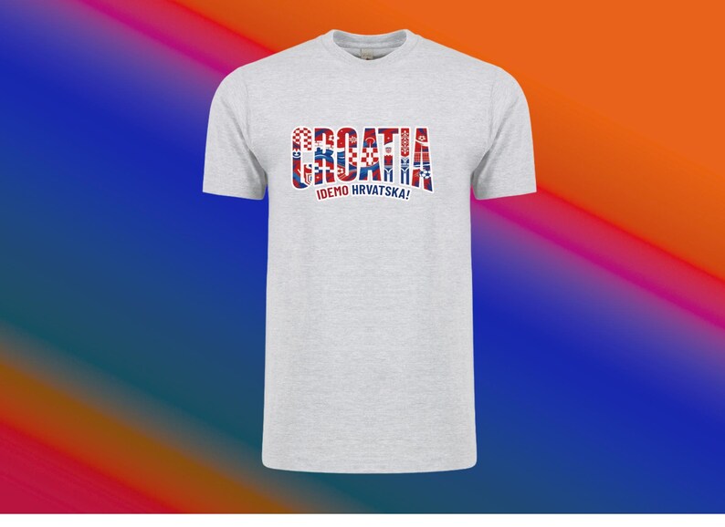 May include: A light gray t-shirt with the word "CROATIA" in a red, white, and blue design across the chest. Below the word is the text "IDEMO HRVATSKA!" in blue. The shirt has short sleeves and a crew neck.
