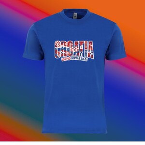 May include: A royal blue t-shirt with the word "CROATIA" in a red, white, and blue design across the chest. Below the word "CROATIA" is the text "IDEMO HRVATSKA!" in white. The shirt has short sleeves and a crew neck.