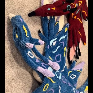Puede incluir: Tres piezas de arte abstracto hechas a mano, de felpa, en tonos de azul y burdeos. Las piezas azules tienen detalles en amarillo, morado y blanco. La pieza burdeos tiene detalles en amarillo, turquesa y negro. Las piezas tienen un aspecto suave y texturizado.