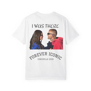 Puede incluir: Camiseta blanca con un gráfico de dos personas, una con gafas de sol y una sudadera con capucha roja. El texto "I WAS THERE" está encima de la imagen, y "FOREVER ICONIC COACHELLA 2026" está debajo.
