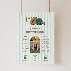 Puede incluir: Un póster vertical de hitos con un fondo de rayas verde claro que presenta un balón de fútbol americano marrón, un casco verde y un poste de meta. Muestra el texto Jackson's FIRST YEAR DOWN, enumera hitos del desarrollo e incluye una foto central.