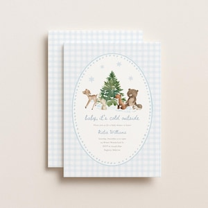 Op de afbeelding: Een lichtblauw en wit geblokte uitnodiging voor een babyshower met een aquarelillustratie van een hert, vos, beer en egel rond een kerstboom. De tekst luidt baby, it's cold outside, Katie Williams en bevat de details van het evenement.