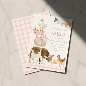 Puede incluir: Una tarjeta de invitación de cumpleaños con una ilustración en acuarela de una torre de animales de granja apilados que incluye una vaca, oveja, cerdo y ganso, con un pollo y un pollito. El texto dice: OINK-GLUCK-BAA-MOO! AMELIA IS TURNING THREE.