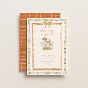 Puede incluir: Una tarjeta de invitación para baby shower de color crema con una ilustración central de un cervatillo, un borde floral y un lazo marrón. El texto dice Fall in Love with Baby Miller, Sophie Miller y detalles del evento. Se encuentra sobre un sobre naranja.
