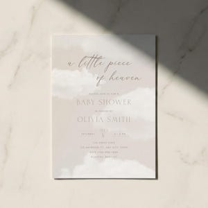 May include: A baby shower invitation featuring a watercolour cloud design. The text reads "a little piece of heaven" and includes details for Olivia Smith's baby shower, including the date, time, and location.