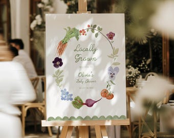 May include: A white rectangular welcome sign on a wooden easel featuring a watercolor wreath of vegetables and flowers. The text reads Locally Grown, Welcome to, Olivia's Baby Shower, and August 10, 20XX. The bottom border has a green scalloped pattern.