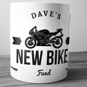 Pode incluir: Caneca de cerâmica branca com uma silhueta preta de uma motocicleta e o texto "Dave's New Bike Fund".