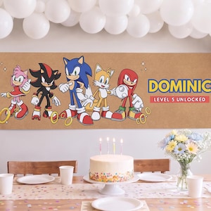 May include: A rectangular banner featuring Sonic the Hedgehog characters Amy Rose, Shadow, Sonic, Tails, and Knuckles. The text reads DOMINIC and LEVEL 5 UNLOCKED in blue and red. The background is a light brown color with gold ring graphics.