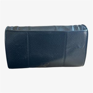 May include: A black leather clutch with a textured surface. The rectangular bag has a flap closure and a stitched design along the top edge. The bag appears to be made of high-quality leather.