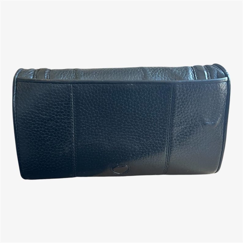 May include: A black leather clutch with a textured surface. The rectangular bag has a flap closure and a stitched design along the top edge. The bag appears to be made of high-quality leather.