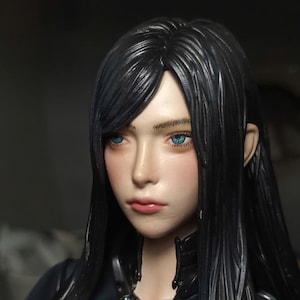 K&ouml;nnte beinhalten: Ein detaillierter Kopf einer Sammlerfigur mit langem, glattem schwarzem Haar, leuchtend blauen Augen und einem neutralen Gesichtsausdruck. Die Haut hat ein glattes, realistisches Finish mit einem dezenten rosa Rouge auf den Wangen und Lippen.