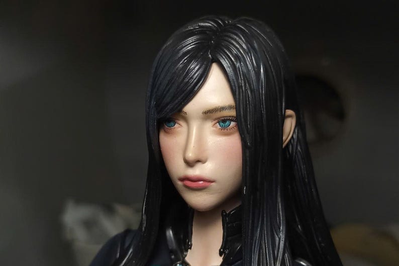 K&ouml;nnte beinhalten: Ein detaillierter Kopf einer Sammlerfigur mit langem, glattem schwarzem Haar, leuchtend blauen Augen und einem neutralen Gesichtsausdruck. Die Haut hat ein glattes, realistisches Finish mit einem dezenten rosa Rouge auf den Wangen und Lippen.
