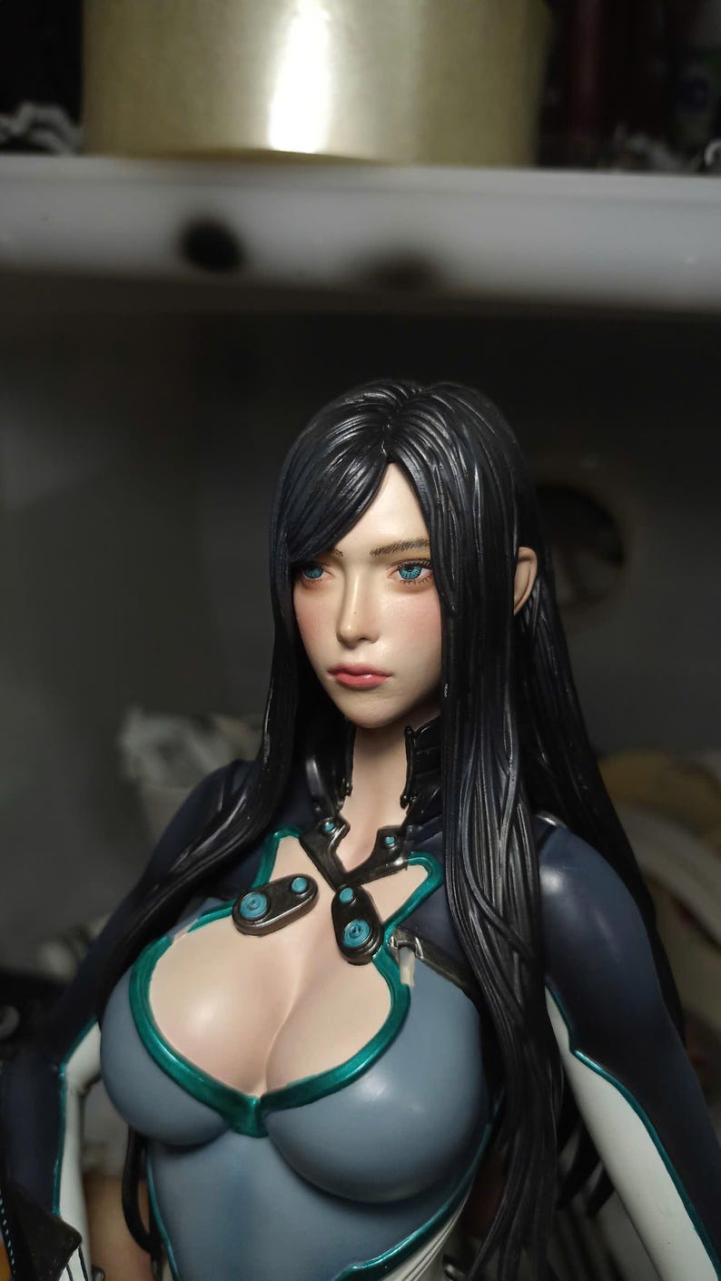 K&ouml;nnte beinhalten: Eine detaillierte Figur, die einen Charakter mit langem, glattem schwarzem Haar, leuchtend blauen Augen und einem neutralen Ausdruck darstellt. Die Figur tr&auml;gt ein eng anliegendes dunkelblau-graues Outfit mit t&uuml;rkisfarbenen Akzenten am Ausschnitt.