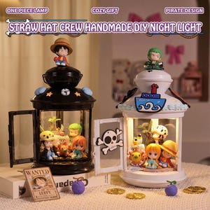 Puede incluir: Dos luces de noche decorativas con temática pirata. Una es negra, la otra blanca. Cada una tiene una puerta de cristal y presenta figuras en miniatura en el interior. El texto "STRAW HAT CREW HANDMADE DIY NIGHT LIGHT" es visible.