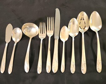 May include: A set of ten silver-plated utensils, including a butter knife, two forks, a serving spoon, a slotted spoon, and four teaspoons. The utensils have a floral design.