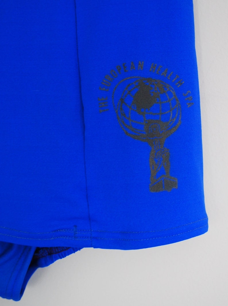 May include: A royal blue fabric with a black and white logo that reads "The European Health Spa". The logo features a globe with a key.