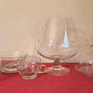 May include: A set of five clear glass serving pieces with etched floral designs. The set includes a large bowl, a small bowl with a lid, a small cup with a handle, a small dome with a base, and a small spoon.