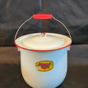 May include: White enamelware bucket with a red rim and handle. The bucket has a lid and a wire handle with a red grip. The words "Coast to Coast Stores" are printed on the front in a yellow and red logo.