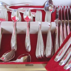 May include: A set of silver cutlery in a red velvet lined wooden box. The set includes spoons, forks, knives, and a serving spoon.