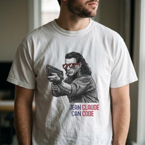 Könnte beinhalten: Weißes T-Shirt mit einer Grafik eines Mannes mit roter Sonnenbrille, der eine Tastatur hält. Der Text "JEAN CLAUDE CAN CODE" ist darunter in Rot und Blau gedruckt. Ein humorvoller Bezug zum Programmieren.