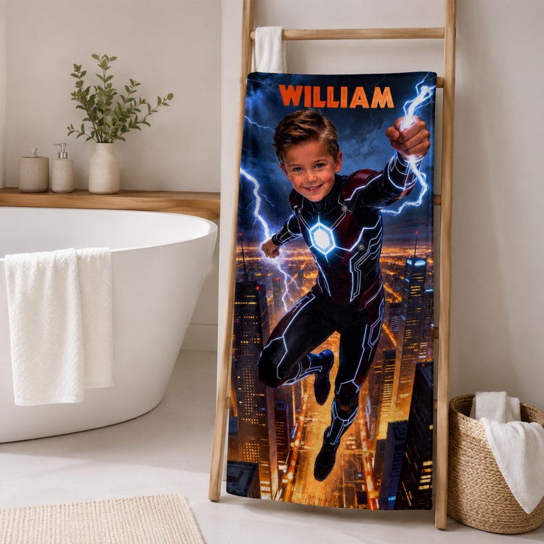Puede incluir: Una toalla de ba&ntilde;o personalizada con tem&aacute;tica de superh&eacute;roe con un ni&ntilde;o en un disfraz de superh&eacute;roe con el nombre "WILLIAM" en naranja. La toalla tiene un fondo de paisaje urbano con rayos.