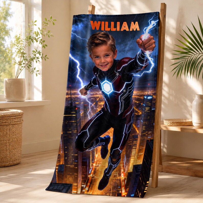 Puede incluir: Una manta de superh&eacute;roe personalizada con un ni&ntilde;o con un traje de superh&eacute;roe, un fondo de paisaje urbano y rayos. El nombre "WILLIAM" se muestra en la parte superior. La manta se exhibe en un estante de madera.