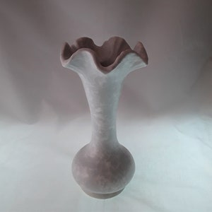 May include: A white ceramic vase with a ruffled top and a bulbous base. The vase has a light gray color and a textured surface.