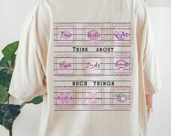 May include: A cream-coloured t-shirt with a graphic on the back. The graphic includes the words "True, Noble, Right, Pure, Lovely, Admirable, Excellent, Gentle, Philippians" in decorative frames.