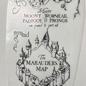 May include: A black and white decal featuring a castle illustration with the text 'Messrs MOONY WORMTAIL PADFOOT & PRONGS are proud to present' and 'The MARAUDERS MAP' along with a banner reading 'HOGWARTS' and a scroll at the top with Latin text.