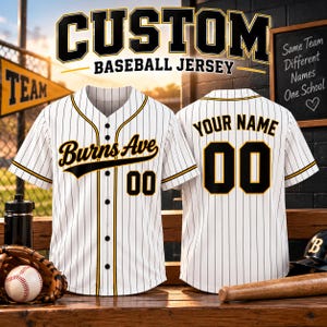 Puede incluir: Una camiseta de béisbol blanca con rayas finas negras, ribetes negros y dorados, y botones negros. El frente presenta el texto Burns Ave y el número 00 en negro con bordes dorados. La parte posterior muestra Your Name y el número 00.