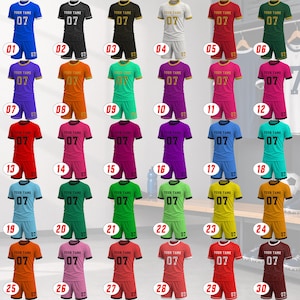 Peut inclure: Une collection de trente ensembles de maillots et shorts de sport de diff&eacute;rentes couleurs, chacun portant le texte 'YOUR TAME' et le num&eacute;ro '07' sur la poitrine. Les ensembles incluent des couleurs unies et des rayures, num&eacute;rot&eacute;s par un cercle rouge.