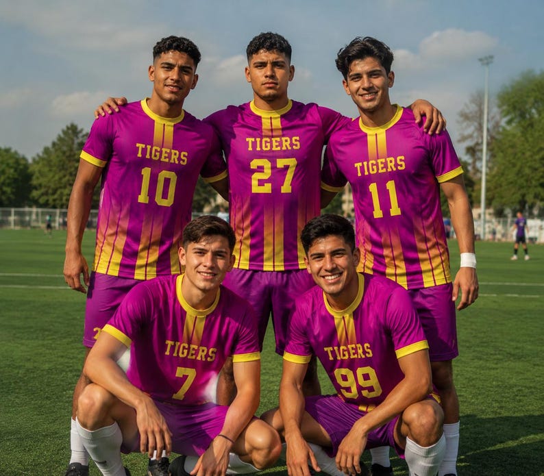 Peut inclure: Cinq joueurs de football portant des maillots assortis violets et jaunes avec le mot TIGERS et des num&eacute;ros uniques 10, 27, 11, 7 et 99 imprim&eacute;s sur le devant. Les maillots pr&eacute;sentent un motif &agrave; rayures verticales d&eacute;grad&eacute;es et des bords jaunes.