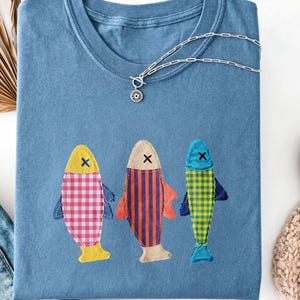 Camiseta de manga corta con cuello redondo, estampado patchwork, cuadros, rayas y tres peces, con apliques vintage de estilo náutico costero para pesca en la playa, lavado mineral.