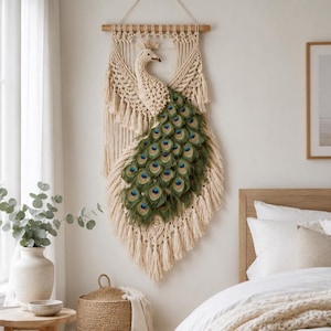 Puede incluir: Un tapiz de pared de macramé con un pavo real, con cuerpo y alas color crema, y un abanico de plumas de pavo real verdes y azules. La obra de arte mural está suspendida de una barra de madera, añadiendo un toque bohemio.