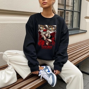May include: Black sweatshirt featuring a graphic of a character with red and white accents and the word "Douma" in red. The sweatshirt is part of a clothing collection.