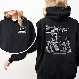May include: Black hoodie with a white "GLOCK PERFECTION" logo on the front. The back features a detailed white diagram of a firearm. The hoodie has a hood and long sleeves, suitable for casual wear.