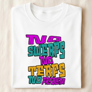 May include: A white short-sleeved t-shirt featuring a multi-coloured graphic print with the text "TWO SWERFS NO TERFS NO PROBLEM" in a bold, blocky font. The letters are coloured in alternating shades of bright pink, teal, and golden yellow.