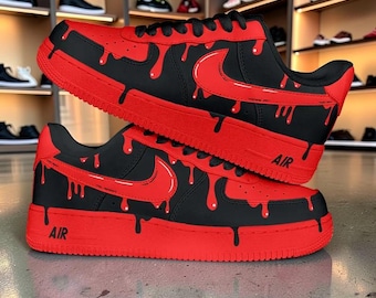 May include: Pair of black and red sneakers with a unique drip design. The sneakers feature a red sole, laces, and Nike swoosh, with red drips cascading down the black upper. The word "AIR" is printed on the side.