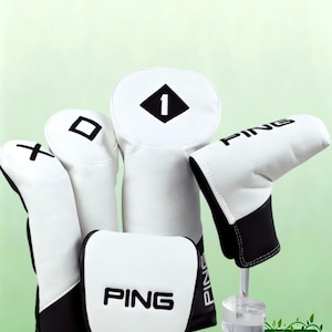 Könnte beinhalten: Ein Set aus weißen und schwarzen Golfschlägerhauben mit dem PING-Markennamen in schwarzer Schrift. Die Hauben umfassen eine Driver-Haube mit der Nummer 1, eine Fairwayholz-Haube mit einem Quadrat-Symbol und eine Hybrid-Haube mit einem Pluszeichen.