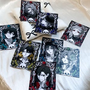 May include: A collection of seven rectangular acrylic art prints featuring anime-style character portraits surrounded by intricate floral and skeletal motifs, each topped with a small colored heart-shaped gem accent.